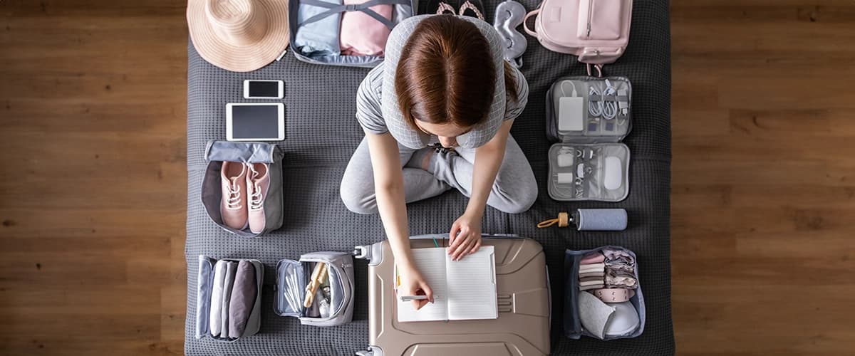 Woman sits on the floor packing a suitcase for vacation