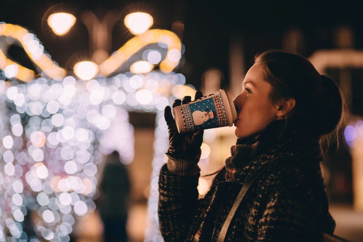 Woman sips a hot drink at a Christmas market