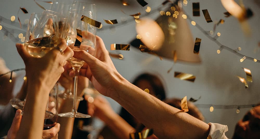 Three people clink champagne glasses at New Year's