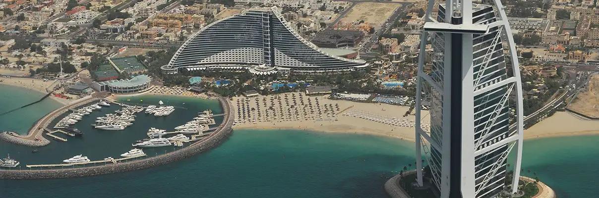 View of a luxurious beach with boats and fancy buildings on the coast of Dubai, United Arab Emirates