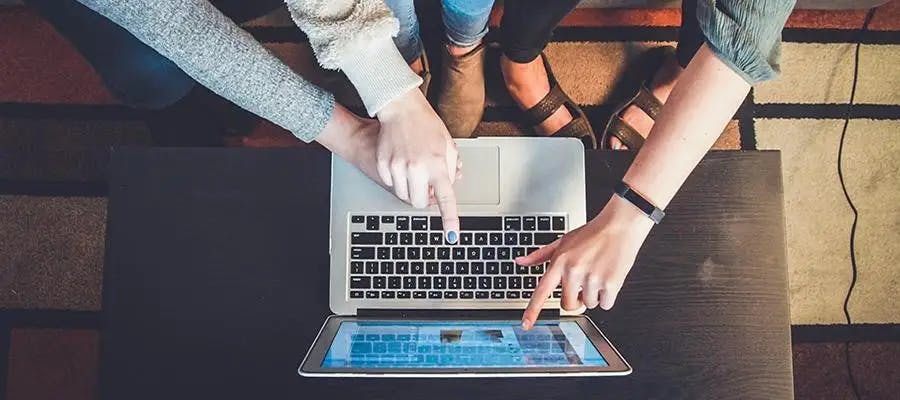 Group of people point at a laptop screen