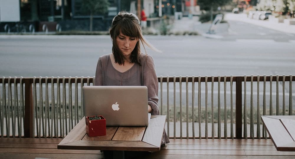 woman working on laptop at an outdoor cafe