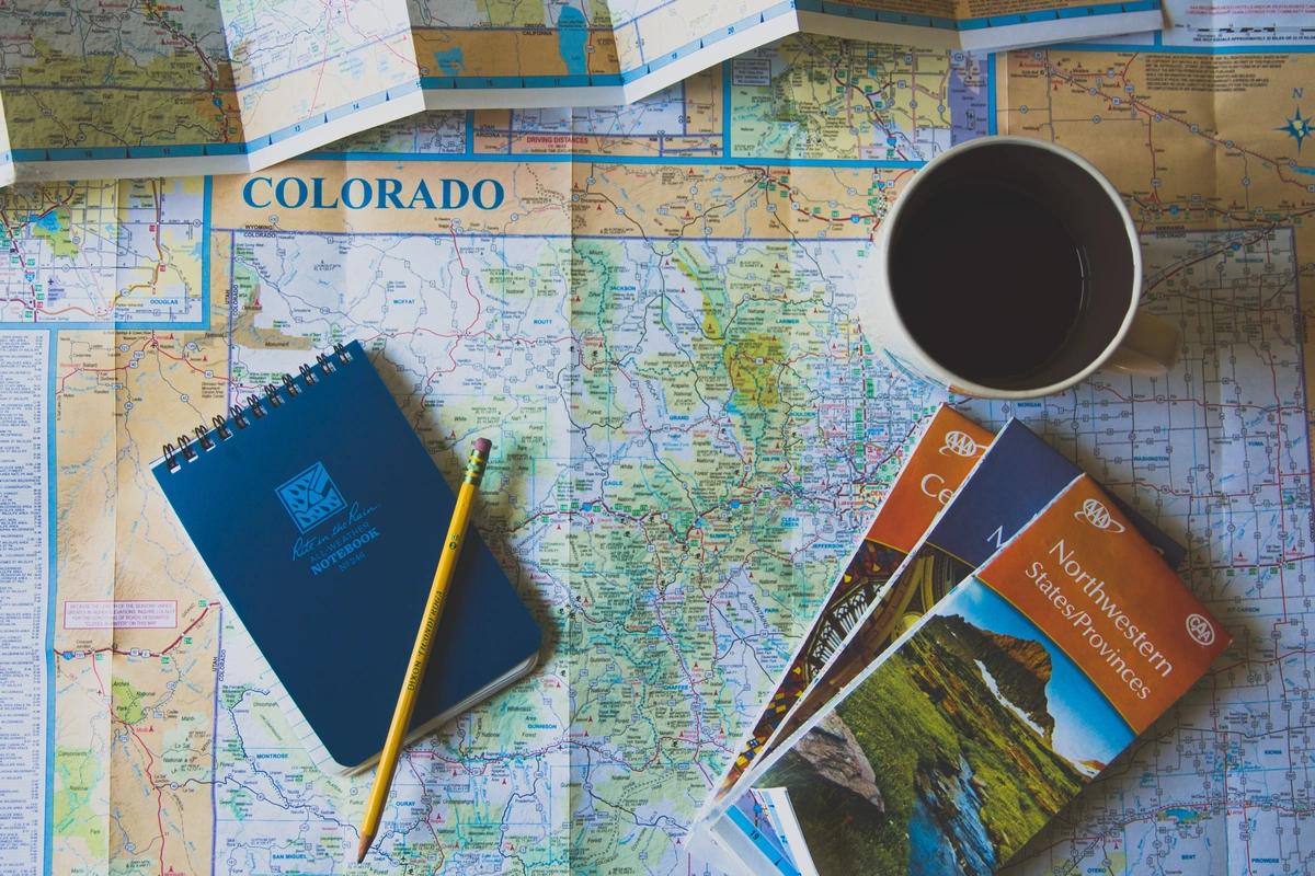 Small notebook, pencil, and road maps on a table