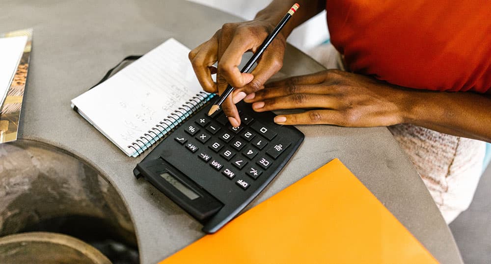 Woman typing on a calculator and taking notes