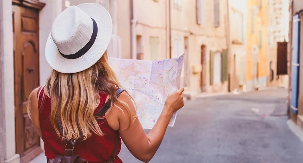 Woman standing in a winding European street, looking at a paper map