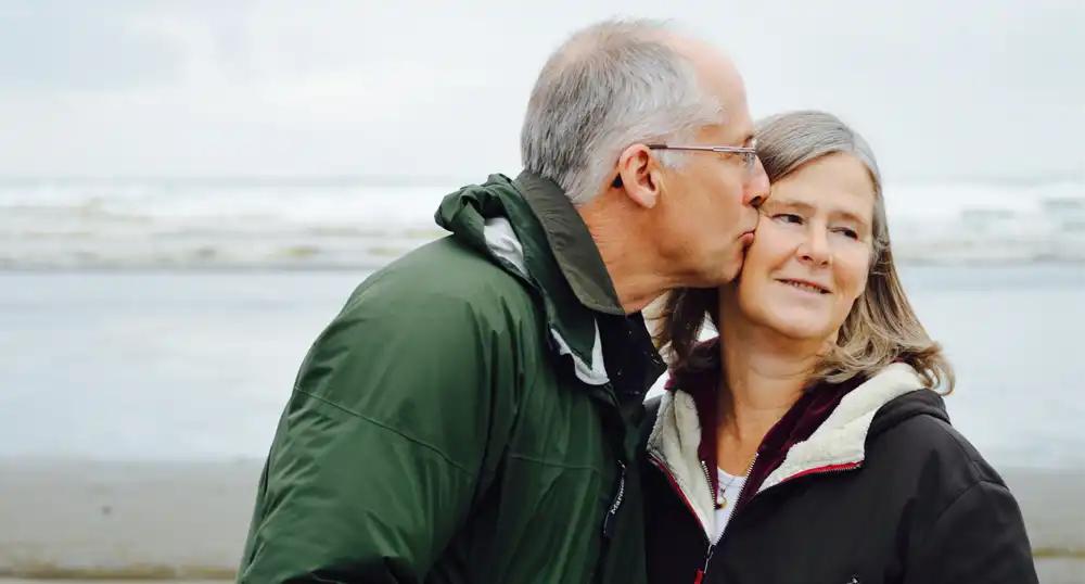 Older gentleman kisses wife on temple