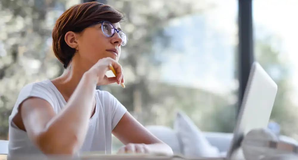 Woman sitting at desk, thinking