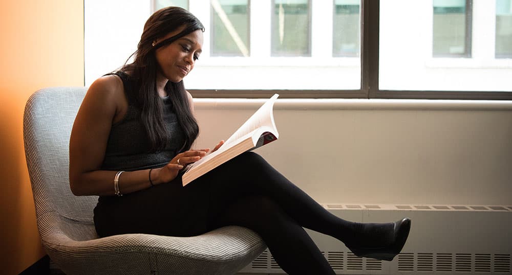 Woman sitting in a chair reading a book.